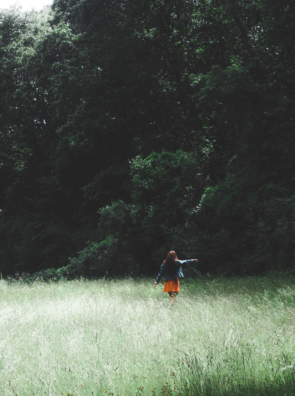 Woman walking in a clearing with her arm outstretched